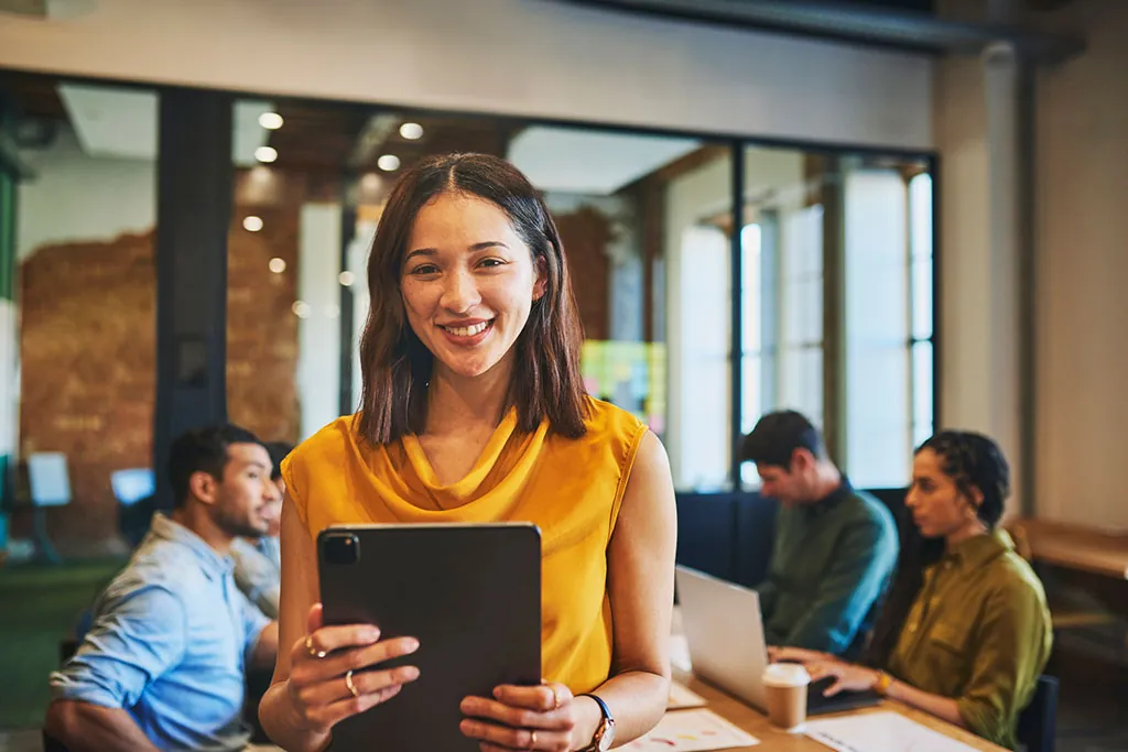 Lächelnde Frau mit Tablet im Team-Meeting